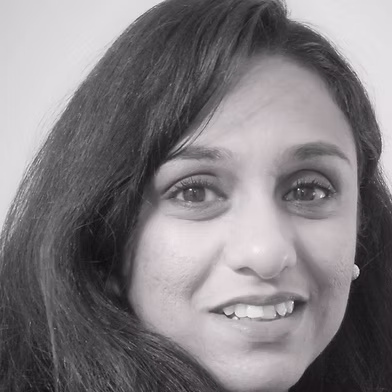 Close-up portrait of a smiling woman with dark hair looking at the camera.