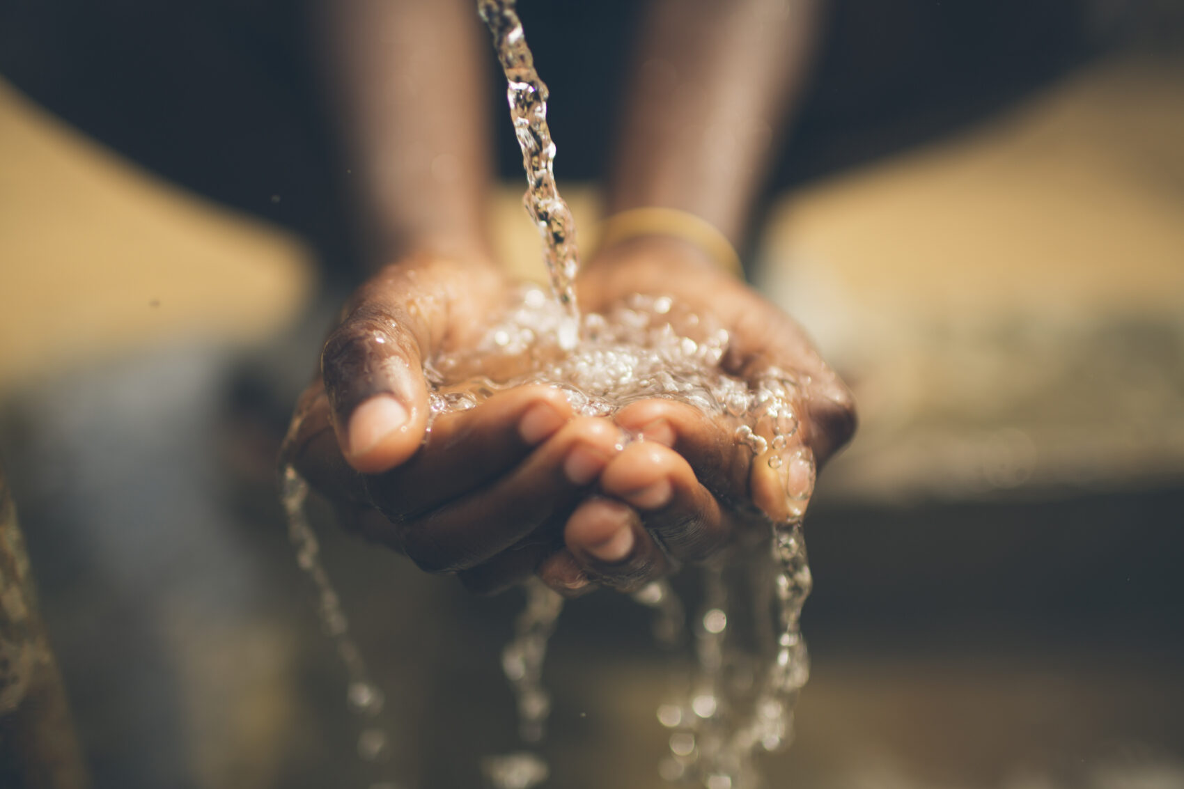 Hands cupping a stream of flowing water, droplets splashing over wet skin.0.8